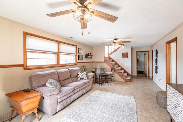 living room featuring stairway, light tile patterned floors, a ceiling fan, and visible vents