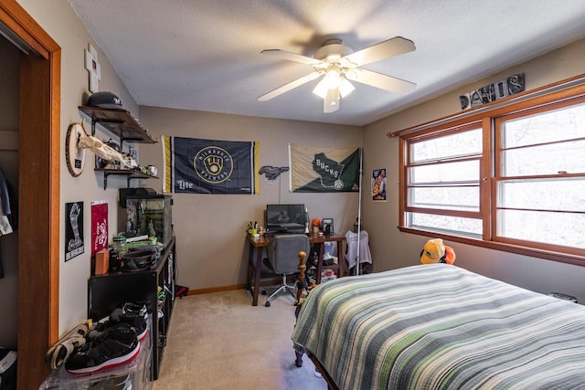 bedroom featuring baseboards, light colored carpet, a textured ceiling, and ceiling fan