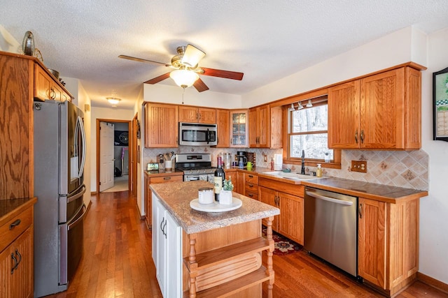 kitchen with a sink, dark wood-style floors, brown cabinetry, and stainless steel appliances