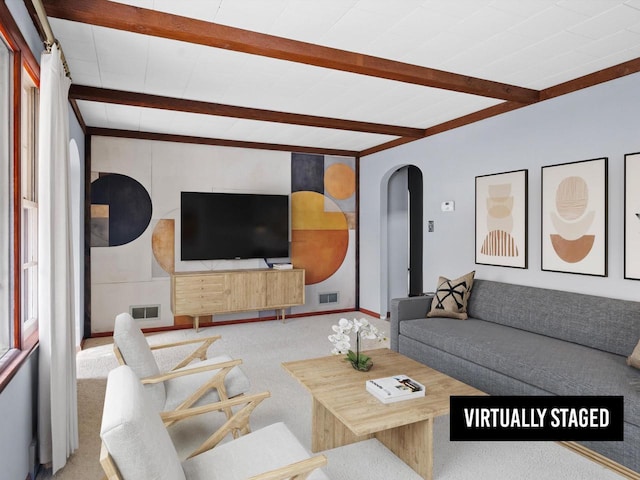 carpeted living area featuring beamed ceiling, arched walkways, and visible vents