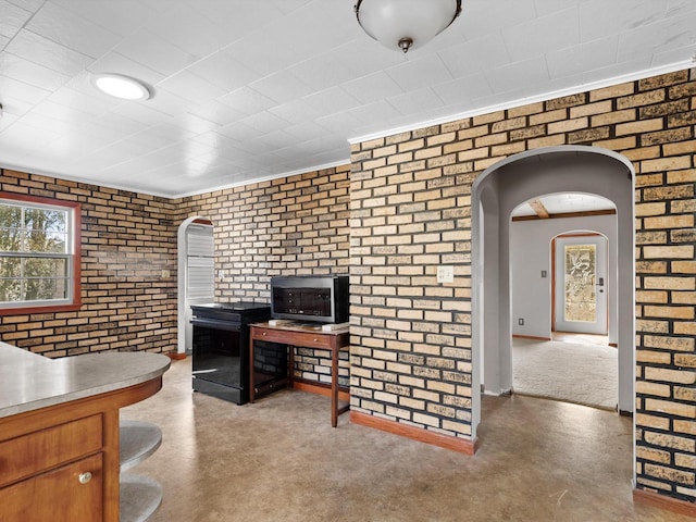 home office featuring arched walkways, finished concrete floors, brick wall, and baseboards