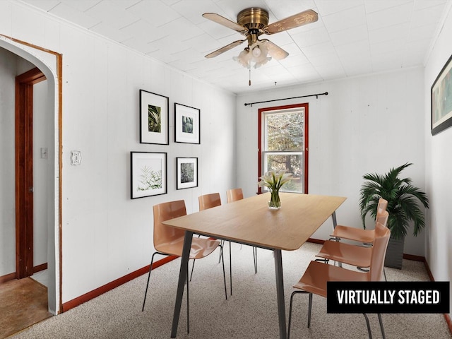 dining space with baseboards, arched walkways, carpet, and ceiling fan