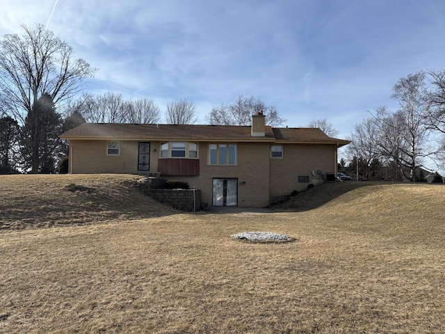 back of property featuring a lawn and a chimney