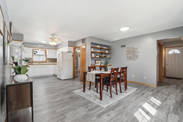 dining room with a ceiling fan, light wood-style flooring, baseboards, and visible vents