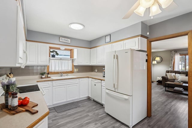 kitchen with a sink, light wood-type flooring, white appliances, and light countertops