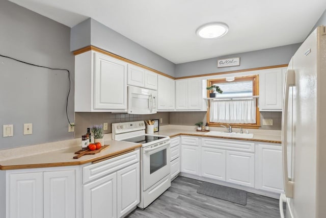 kitchen with backsplash, light countertops, white cabinets, white appliances, and a sink