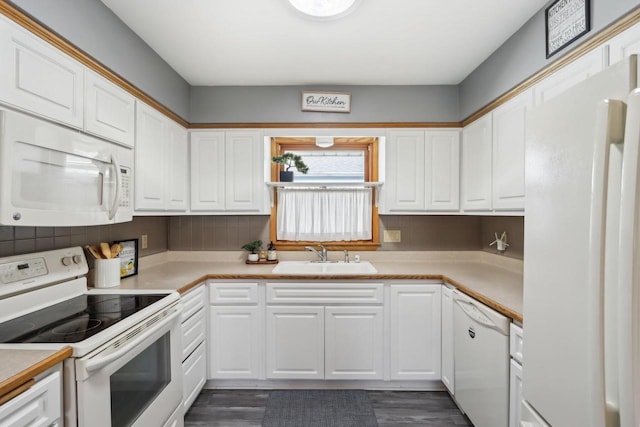 kitchen with a sink, white appliances, light countertops, and white cabinetry