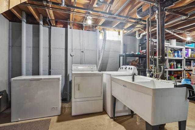 clothes washing area featuring laundry area, washing machine and dryer, and a sink