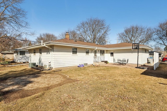 rear view of house with a yard, central AC, and a chimney