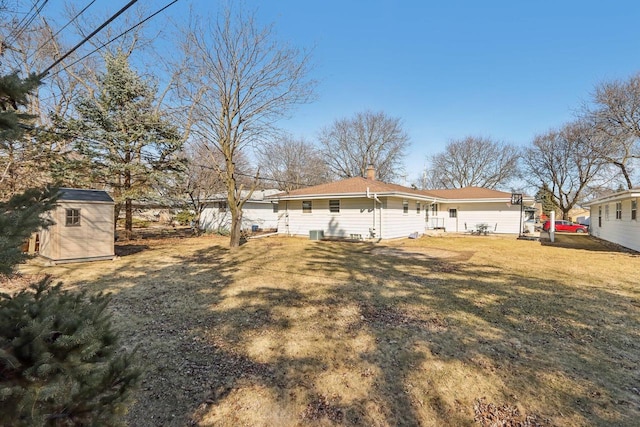 back of house with a shed, a lawn, a chimney, and an outdoor structure