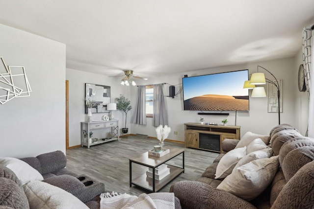 living room with a fireplace, baseboards, ceiling fan, and wood finished floors