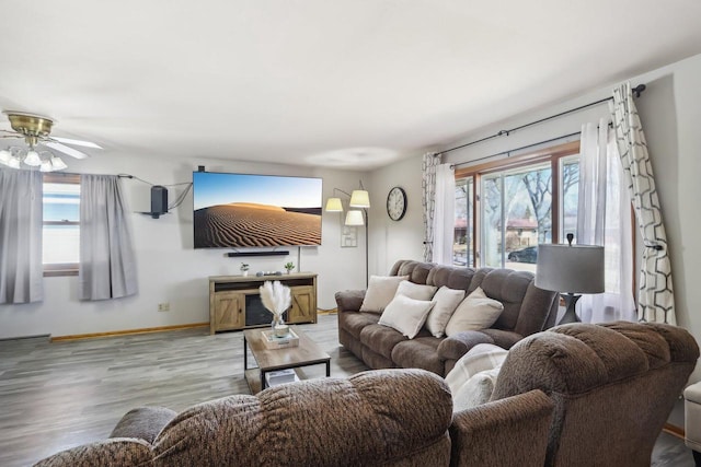 living area with plenty of natural light, baseboards, light wood-type flooring, and ceiling fan