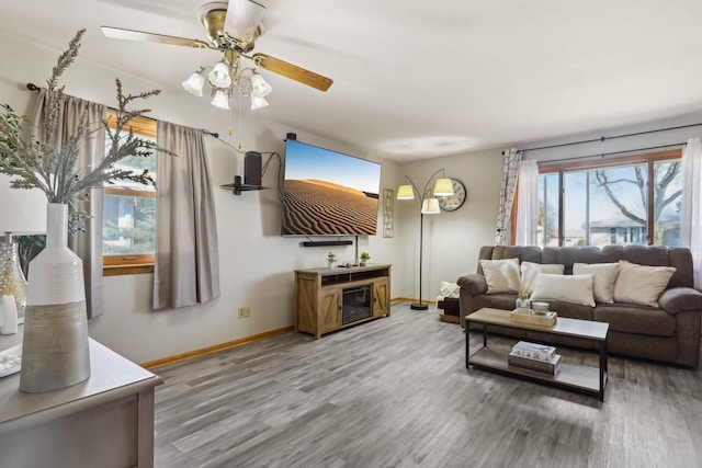 living area featuring ceiling fan, baseboards, and light wood-style floors