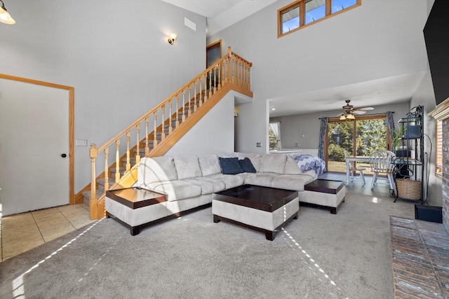 carpeted living area featuring tile patterned flooring, a ceiling fan, stairs, and a towering ceiling