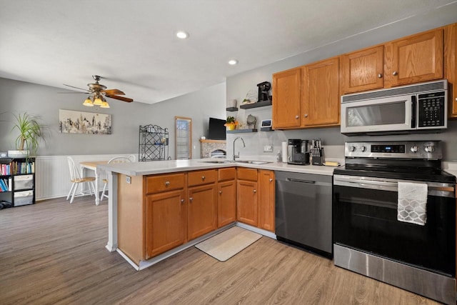 kitchen featuring a sink, open shelves, stainless steel appliances, a peninsula, and light countertops