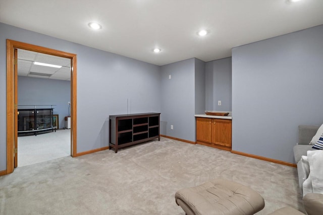 sitting room with recessed lighting, a drop ceiling, baseboards, and light colored carpet