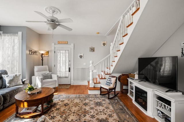 living room with stairs, wood finished floors, and ceiling fan