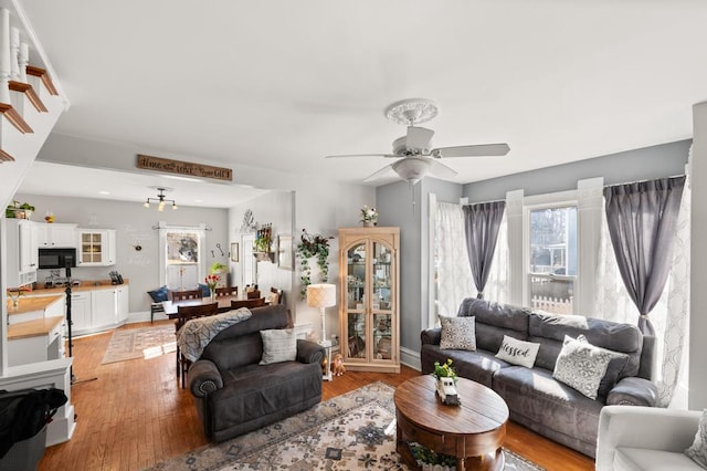 living room with baseboards, a healthy amount of sunlight, light wood-style flooring, and a ceiling fan