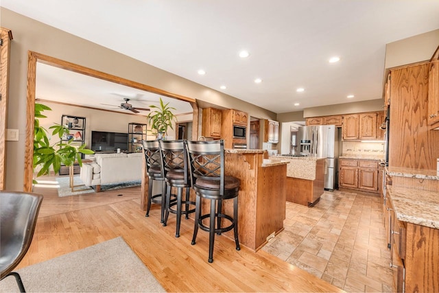 kitchen featuring built in microwave, light stone countertops, a breakfast bar area, and stainless steel fridge with ice dispenser