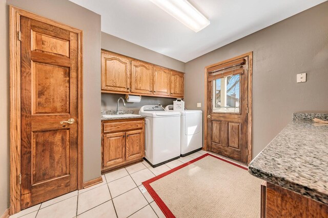 laundry area with light tile patterned floors, cabinet space, washer and dryer, and a sink