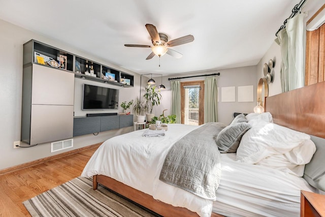 bedroom featuring visible vents, a ceiling fan, wood finished floors, baseboards, and access to exterior