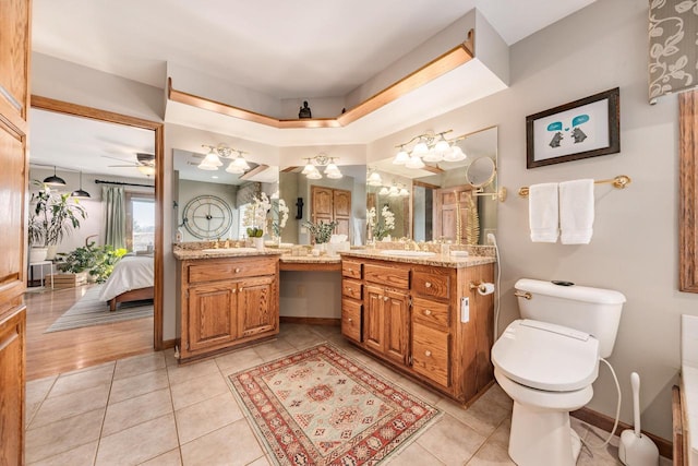 bathroom featuring tile patterned floors, toilet, ensuite bath, baseboards, and vanity