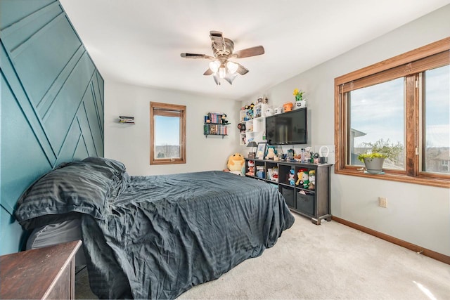 bedroom featuring light colored carpet, a ceiling fan, and baseboards