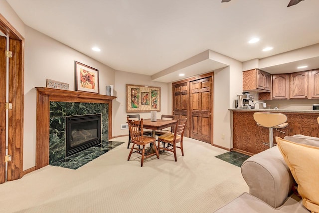 dining room with recessed lighting, a fireplace, light colored carpet, and baseboards