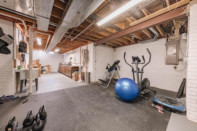 exercise room with electric panel and brick wall