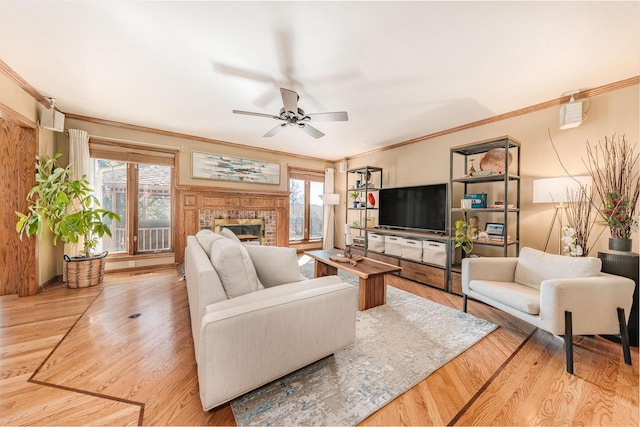 living area with a glass covered fireplace, crown molding, wood finished floors, and a wealth of natural light