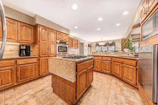 kitchen with stone finish flooring, tasteful backsplash, a center island, a peninsula, and brown cabinetry