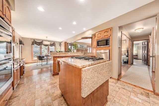 kitchen featuring a peninsula, a center island, stone tile flooring, and stainless steel appliances