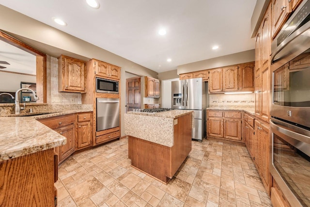 kitchen with a sink, light stone counters, a kitchen island, stainless steel appliances, and decorative backsplash