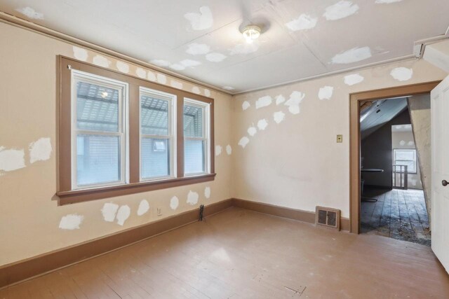 empty room featuring visible vents, baseboards, and hardwood / wood-style floors