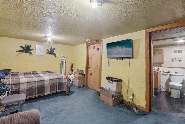 carpeted bedroom with visible vents, a textured ceiling, and ensuite bath