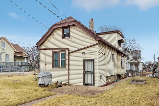 rear view of house with a lawn, a chimney, and fence