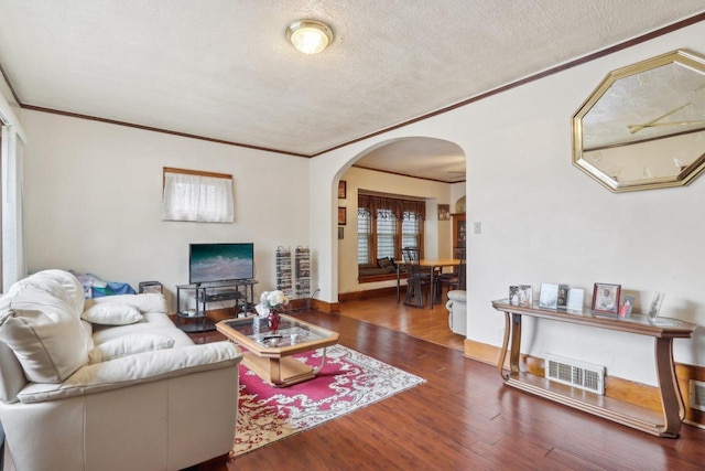 living room featuring visible vents, arched walkways, a textured ceiling, and wood finished floors