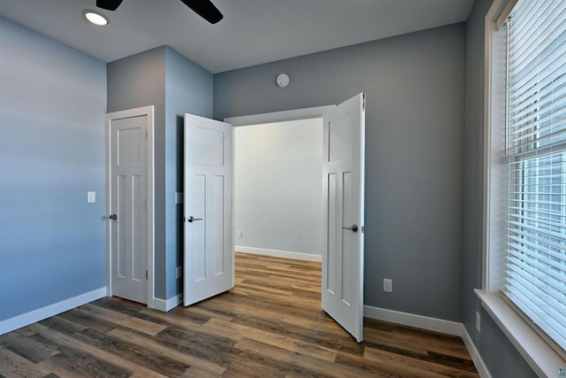 unfurnished bedroom with baseboards and dark wood-style flooring