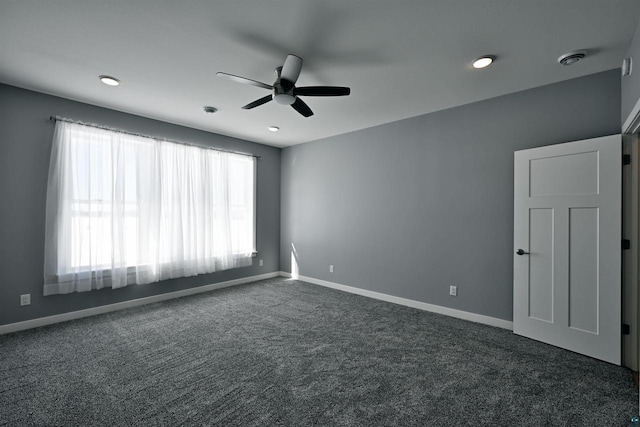 unfurnished room with dark colored carpet, visible vents, baseboards, and ceiling fan