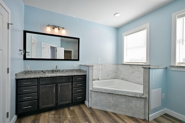 bathroom with a wealth of natural light, a garden tub, and wood finished floors