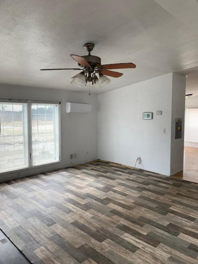 spare room featuring a textured ceiling, a wall mounted air conditioner, and a ceiling fan