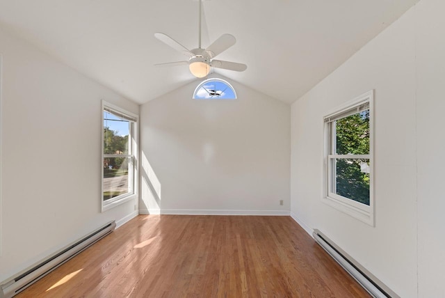 unfurnished room with a baseboard radiator, baseboards, wood finished floors, and vaulted ceiling