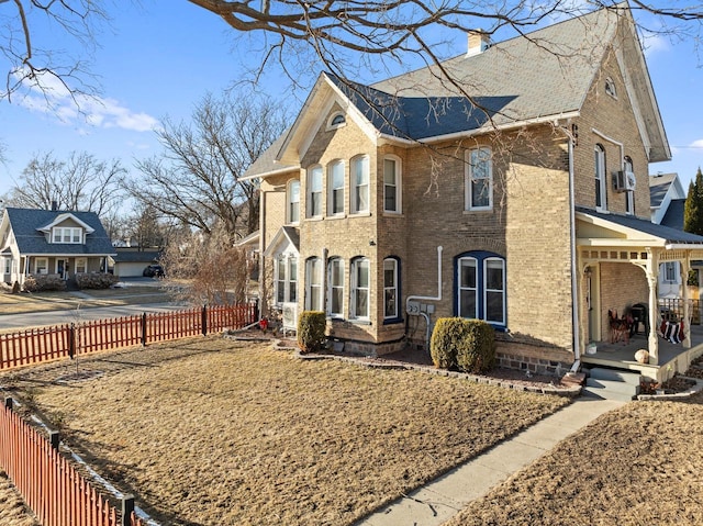 view of side of home featuring brick siding, covered porch, a chimney, and fence