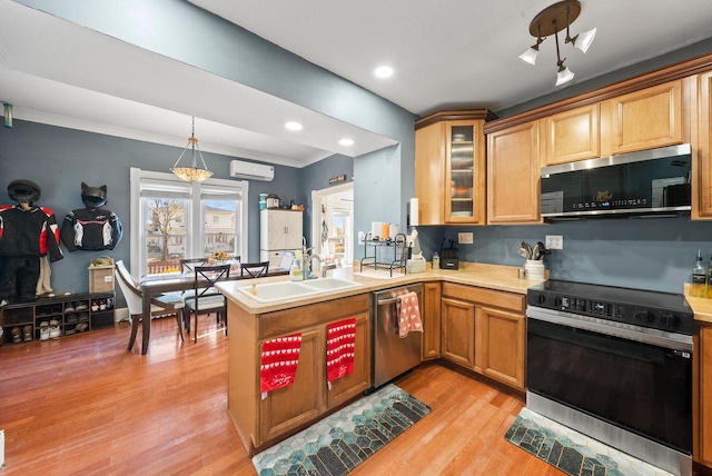 kitchen featuring a wall unit AC, a peninsula, stainless steel appliances, light countertops, and light wood-style floors