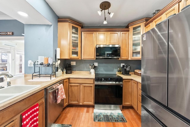 kitchen featuring light countertops, light wood-style flooring, appliances with stainless steel finishes, and a sink