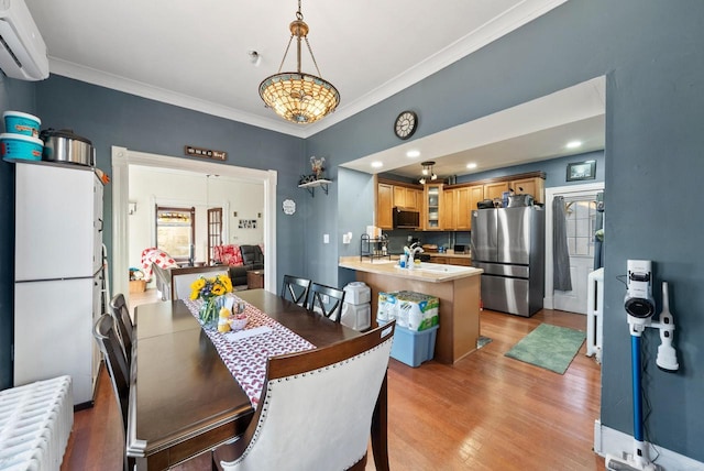 dining room featuring a wall unit AC, crown molding, radiator, and light wood-style floors