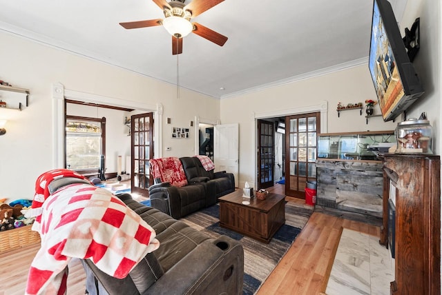 living area with a wealth of natural light, french doors, a ceiling fan, and crown molding