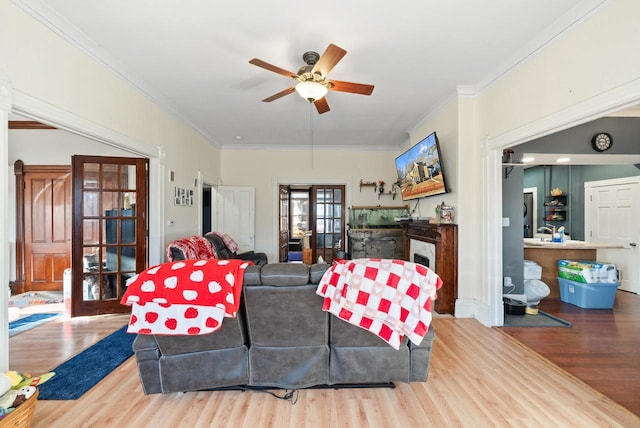 living area featuring wood finished floors, ornamental molding, french doors, and ceiling fan