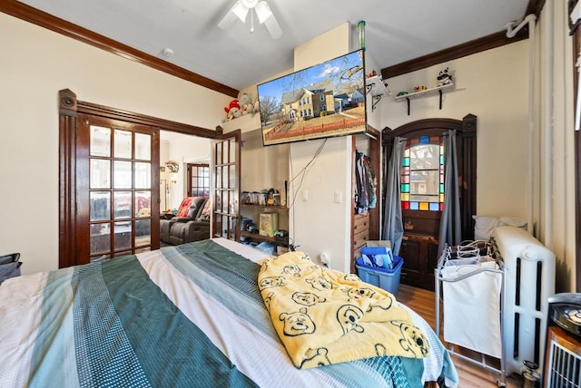 bedroom featuring wood finished floors, ornamental molding, and a ceiling fan