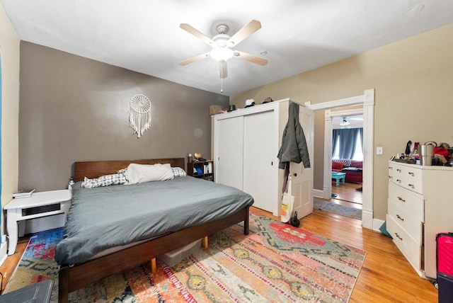 bedroom featuring a closet, baseboards, a ceiling fan, and light wood finished floors